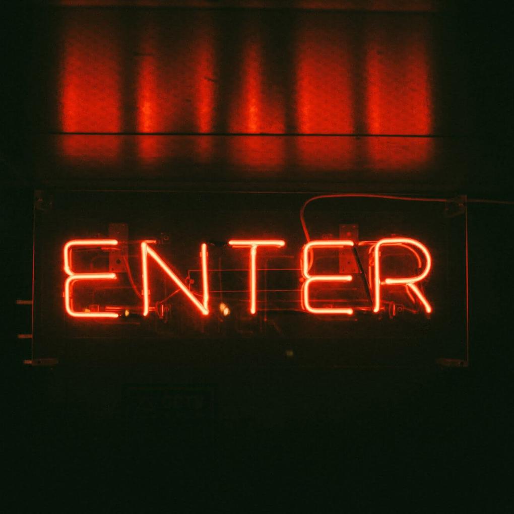 Dunkler Hintergrund mit rotem Schriftzug 'Enter' als Neonlicht
